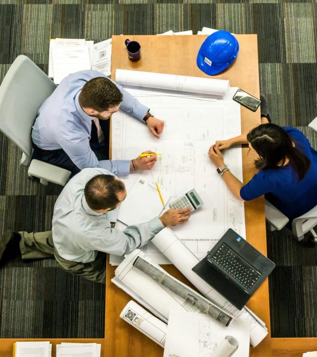 Top view of a team working on construction plans in an office setting.